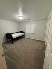 Bedroom featuring a textured ceiling and dark carpet