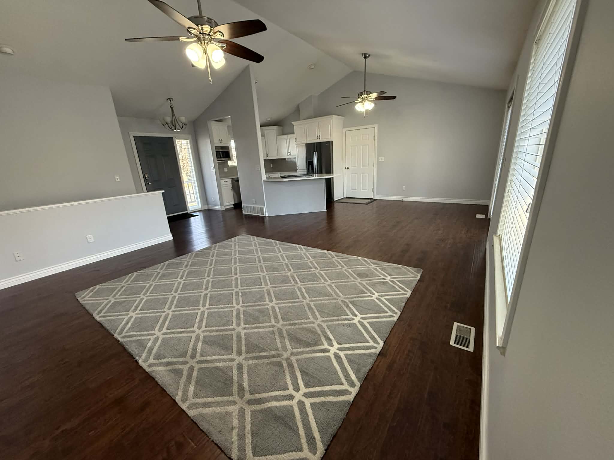 Unfurnished living room featuring a high ceiling, dark wood-style floors, a ceiling fan, and healthy amount of natural light