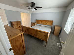 Bedroom featuring dark colored carpet, a textured ceiling, and ceiling fan