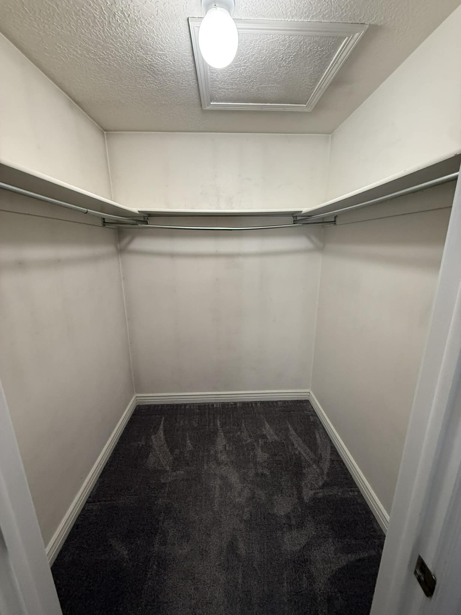 Walk in closet with dark carpet and attic access