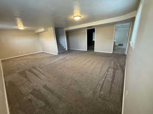 Unfurnished bedroom featuring dark colored carpet and a textured ceiling