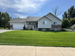 View of front of house with a porch, a garage, a front yard, concrete driveway, and brick siding