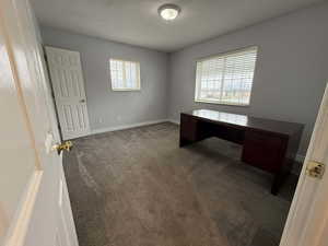 Unfurnished office with dark carpet and a textured ceiling