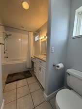 Full bath featuring vanity, shower / bath combo, light tile patterned floors, and a textured ceiling