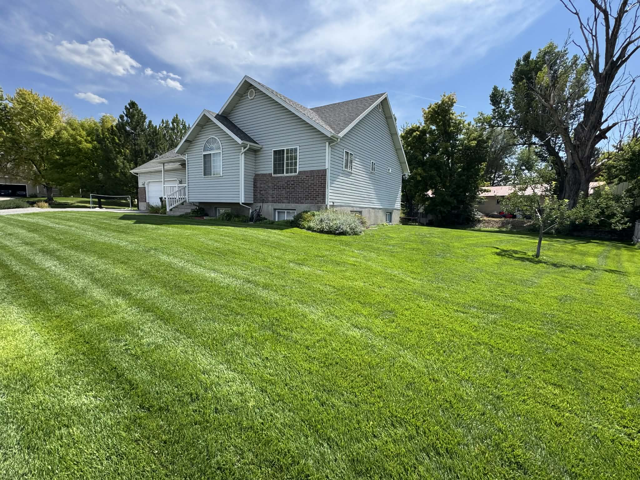 View of property exterior with a lawn, an attached garage, and view of wooded area