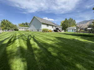 Back of house featuring a trampoline, a lawn, a residential view, and an outdoor structure
