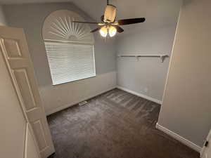 Unfurnished room with dark carpet and a ceiling fan