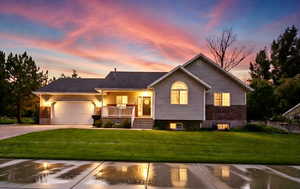 View of front of home featuring a porch, a garage, a front yard, and driveway