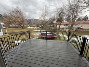 Wooden deck with a trampoline, a mountain view, a lawn, and a residential view