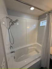 Bathroom with shower / bathtub combination with curtain and a textured ceiling