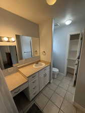 Bathroom with a textured ceiling, vanity, light tile patterned flooring, and a closet