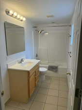 Full bathroom featuring vanity, light tile patterned floors, bathing tub / shower combination, and a textured ceiling