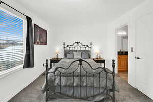 Bedroom featuring ensuite bath and dark colored carpet