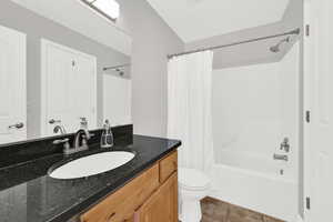 Full bathroom with vanity, shower / tub combo with curtain, and light tile patterned floors