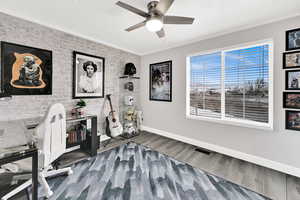 Office featuring crown molding, brick wall, light wood-style flooring, a ceiling fan, and an accent wall