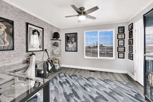 Interior space featuring ornamental molding, a ceiling fan, light wood-type flooring, and brick wall