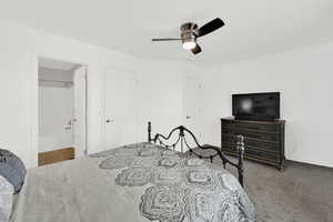Carpeted bedroom featuring ceiling fan and ensuite bath