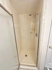 Bathroom with a shower stall and a textured ceiling
