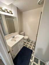 Bathroom with a stall shower, vanity, a textured ceiling, and dark flooring