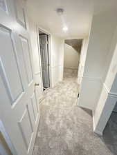 Corridor featuring light colored carpet and baseboards