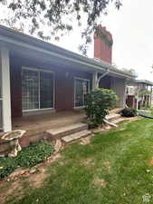 Rear view of property featuring a yard, a chimney, and brick siding