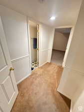 Hall featuring light carpet and a textured ceiling