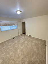 Unfurnished bedroom featuring a textured ceiling and carpet floors