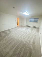Unfurnished bedroom with a baseboard radiator and light carpet