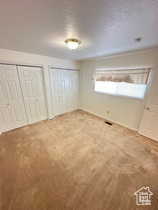 Unfurnished bedroom featuring multiple closets, carpet, and a textured ceiling