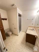Bathroom featuring a shower stall, vanity, and light floors