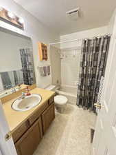 Bathroom with vanity, a textured ceiling, and shower / bath combo