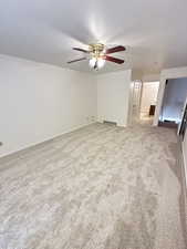 Spare room with light carpet, a ceiling fan, and a textured ceiling
