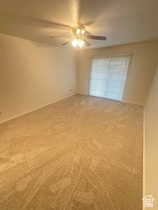Carpeted spare room featuring a ceiling fan
