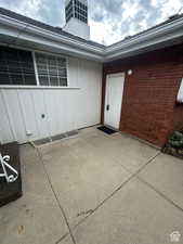 View of exterior entry featuring brick siding, a patio, and board and batten siding