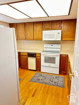 Kitchen featuring light countertops, white appliances, light wood finished floors, and wood finish cabinetry