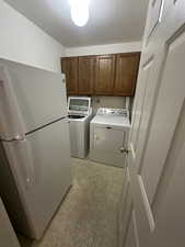 Laundry room with washer and dryer, a textured ceiling, cabinet space, and light flooring