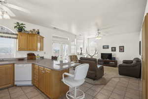 Kitchen with ceiling fan, white dishwasher, open floor plan, and a kitchen bar