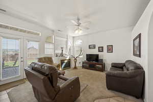Living room featuring ceiling fan, healthy amount of natural light, light colored carpet, and light tile patterned floors