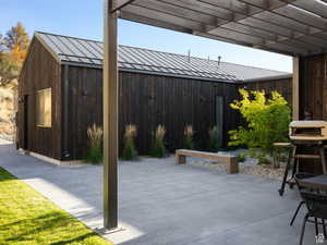 View of patio with grilling area and a pergola