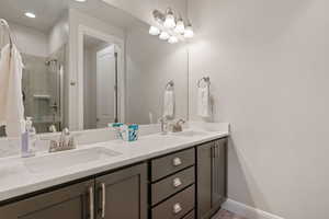 Full bathroom featuring double vanity and tiled shower