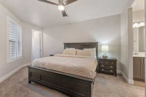 Bedroom featuring ensuite bath, ceiling fan, and light carpet