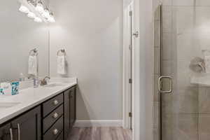 Bathroom with a shower stall, double vanity, and light wood-style floors