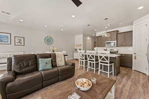 Living room featuring light wood-type flooring, a ceiling fan, and recessed lighting