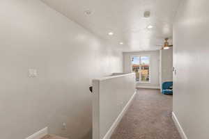 Corridor featuring an upstairs landing, light colored carpet, a textured ceiling, and recessed lighting