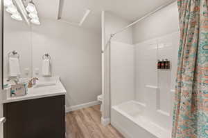 Full bath with vanity, shower / bath combo, and light wood finished floors