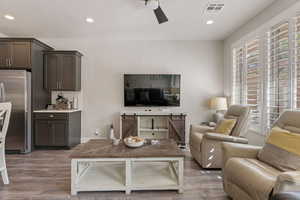 Living room with dark wood-style flooring, a ceiling fan, and recessed lighting