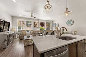 Kitchen with light stone countertops, stainless steel dishwasher, dark wood-style floors, hanging light fixtures, and a textured ceiling