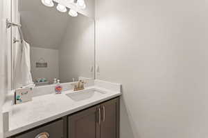 Bathroom with vanity and lofted ceiling