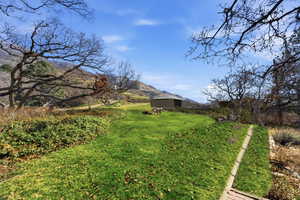 View of green lawn with a mountain view and an outdoor structure