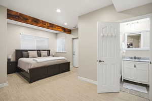 Bedroom with recessed lighting, light colored carpet, ensuite bathroom, and beamed ceiling